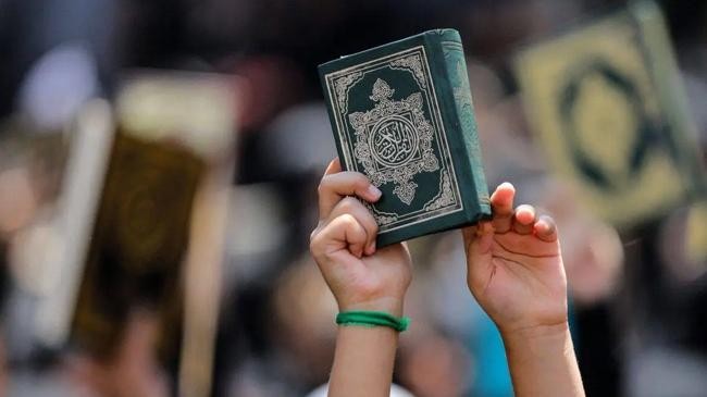 a child raises a copy of the quran