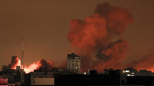 a plume of smoke rises above buildings in gaza city