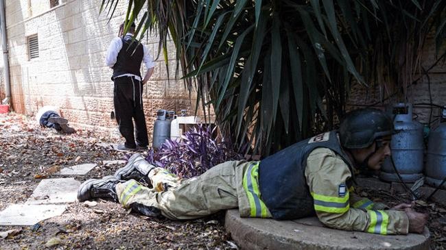 an israeli firefighter lies on the ground as a siren for incoming rockets from lebanon goes off in kiryat shmona northern israel june 19 2024