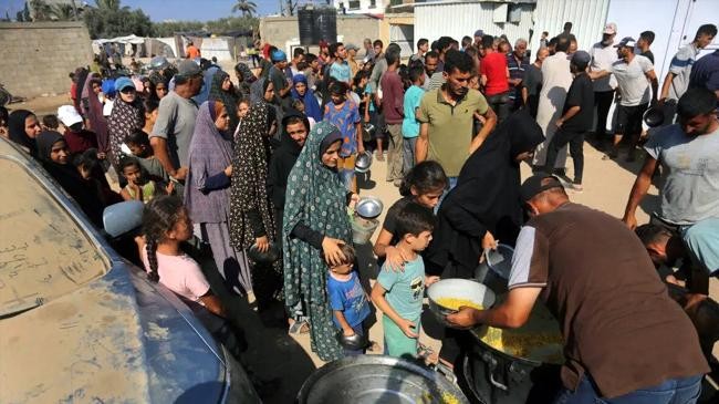 palestinians wait in line to receive food distributed by charities